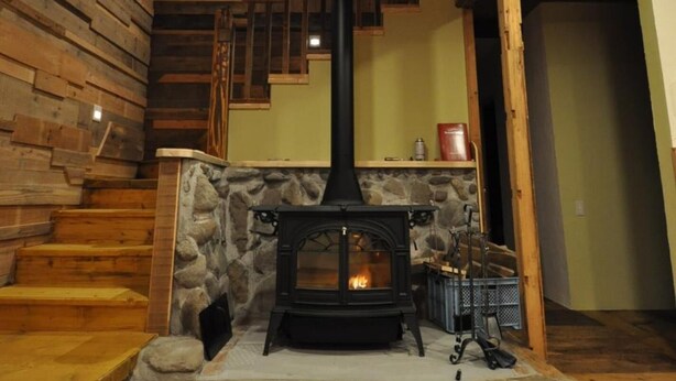 A rustic interior with a stone fireplace, wooden staircase, and a wooden ceiling. - Gufo no Mori Kamifurano (Kamifurano)