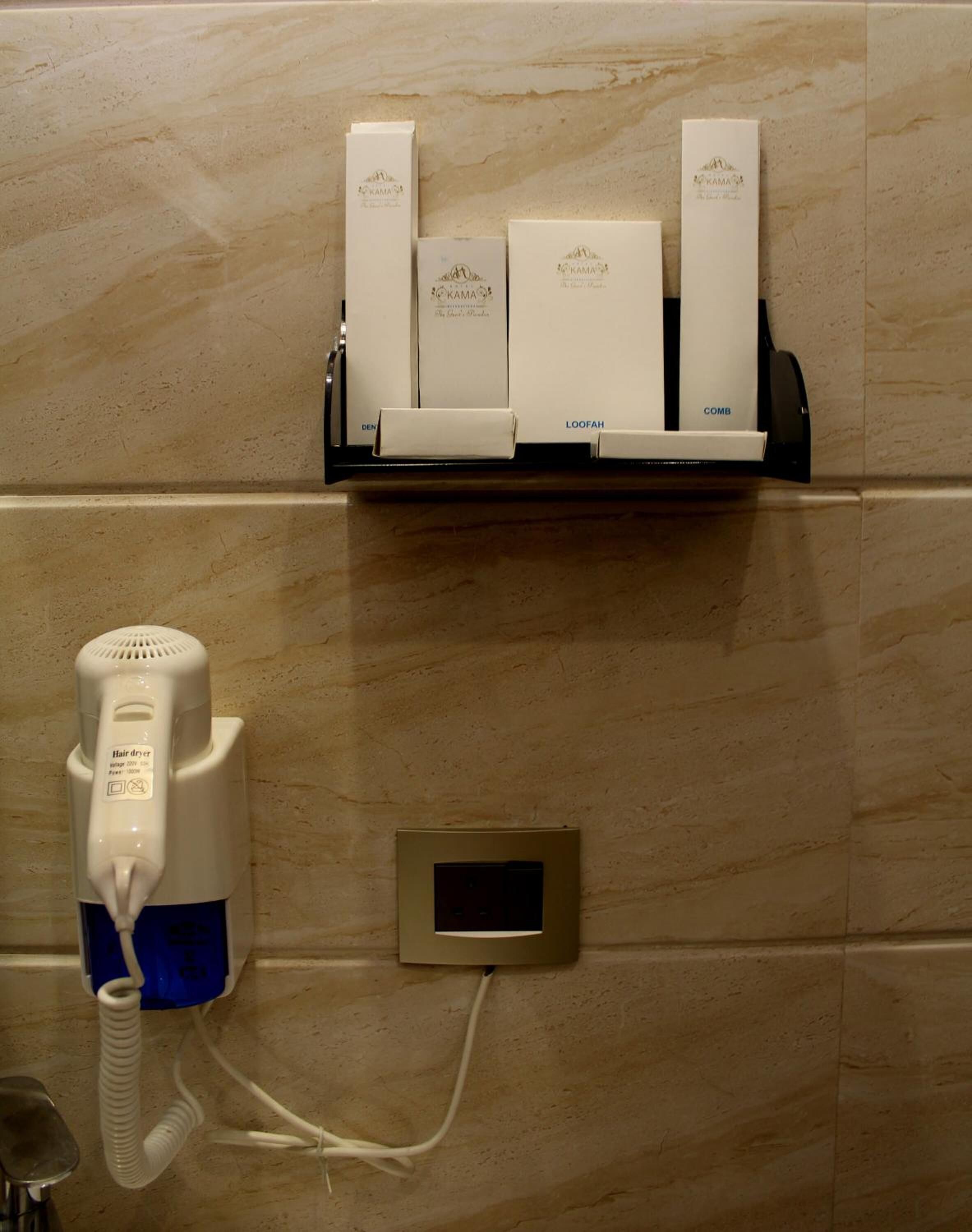 Ein Haartrockner und ein Set an Pflegeprodukten auf einer an der Wand montierten Ablagefläche.