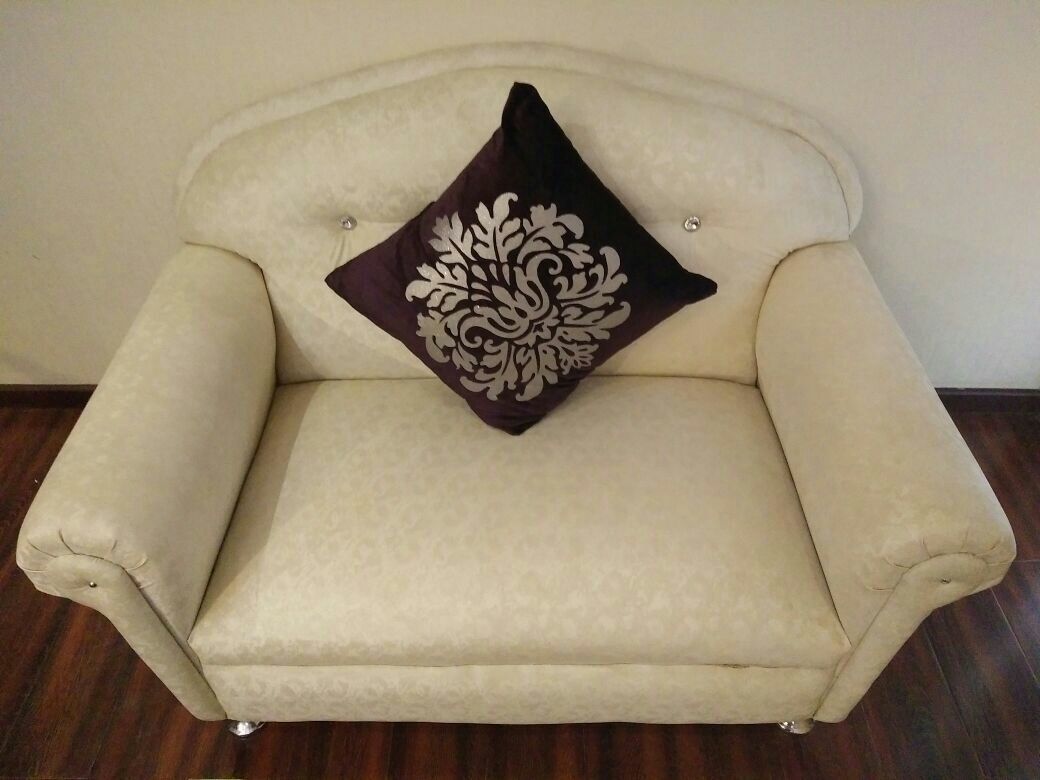 A beige armchair with a decorative pillow.