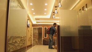 Een moderne hotellobby met een glazen scheidingswand, een trap en een zithoek.