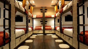 A train compartment with bunk beds, wooden flooring, and a central aisle.