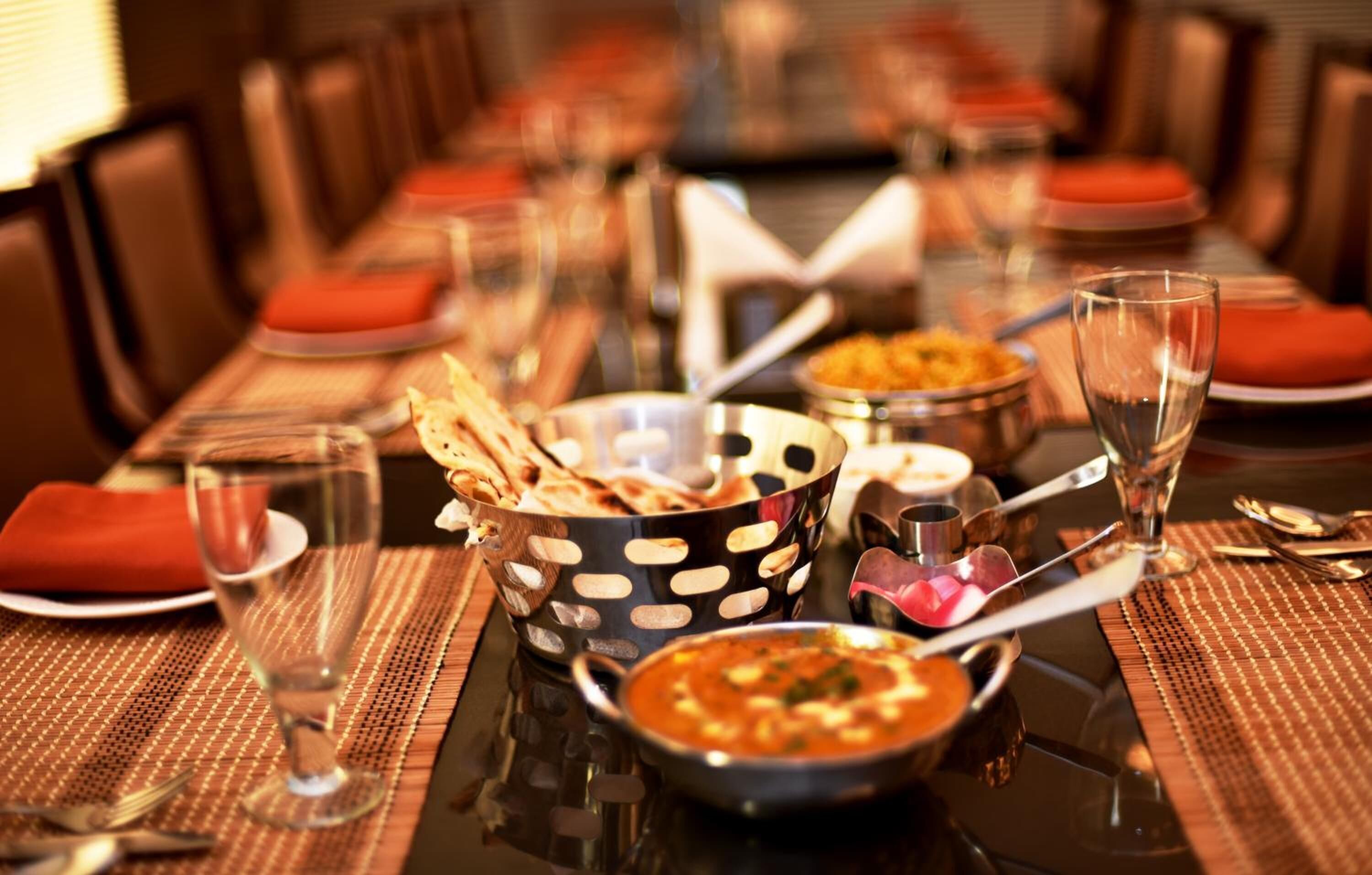 A dining table set with various dishes, including bowls of soup and flatbread, and a clear glass.