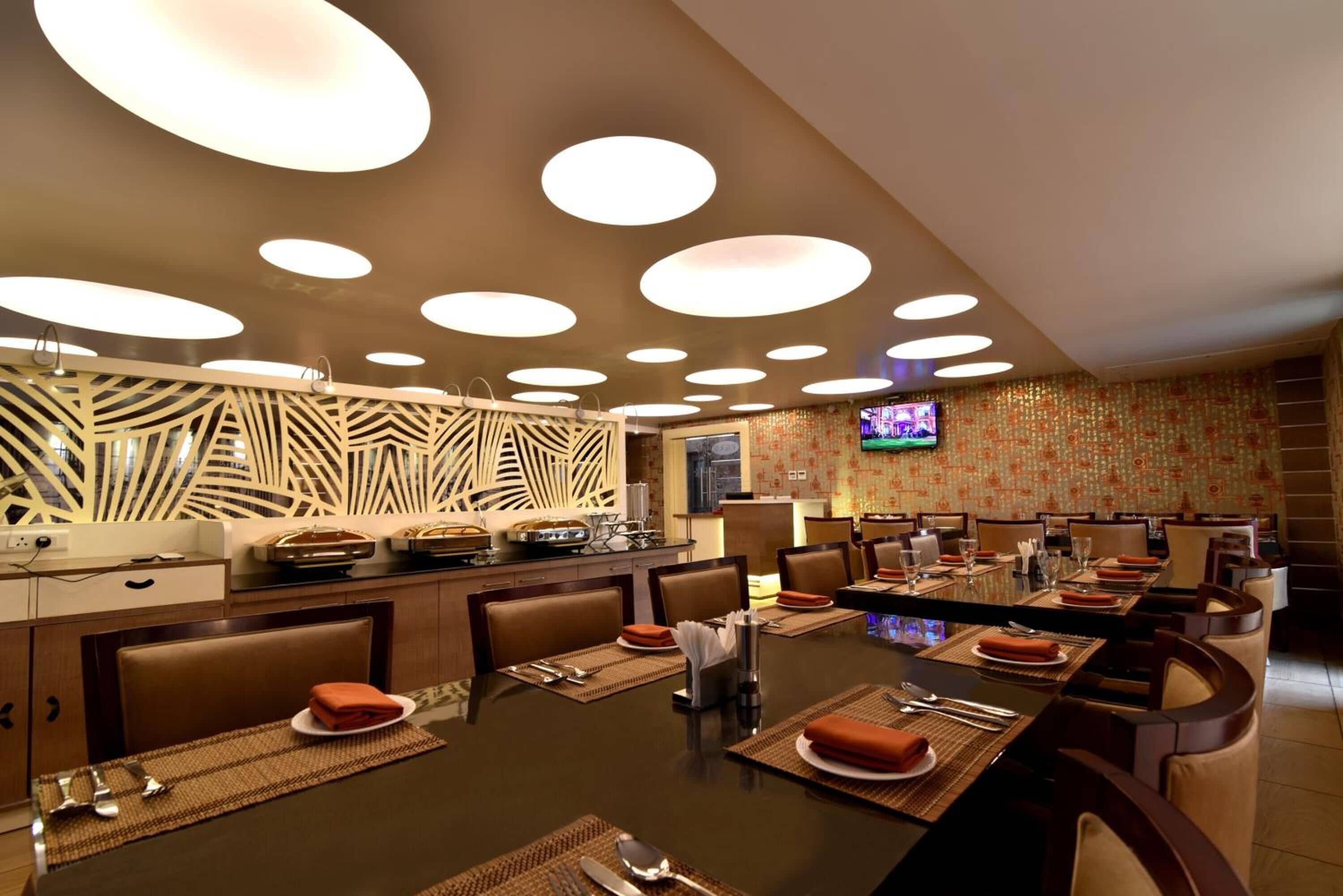 A modern dining area with a long table, multiple chairs, and a television screen.