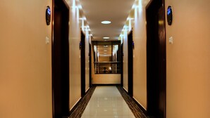 Een hotelhal met een centrale trap, deuren aan beide zijden en een gepoetste vloer.