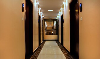Ein Hotel-Flur mit einer zentralen Treppe und Türen an beiden Seiten, sowie einem polierten Boden.
