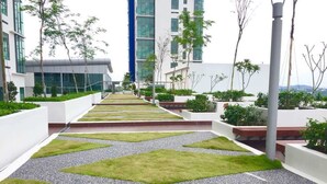 A rooftop garden with geometric grass patterns, white planters, and modern buildings in the background.