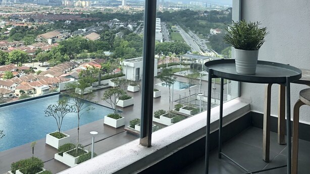 A balcony with a view of a cityscape, a swimming pool, and a potted plant.