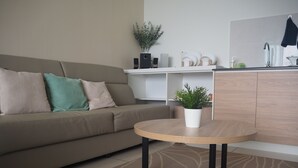 A modern living room with a beige sofa, a round wooden table, and a potted plant.