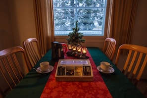 A dining table with a tea box, candles, and a small Christmas tree.