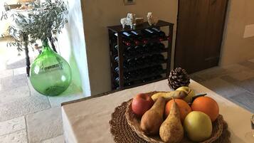 A table with a fruit basket, a green vase, and a wine rack.