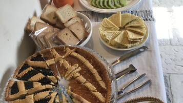 A table with a variety of food items including a pie, sliced fruits, sandwiches, and nuts.