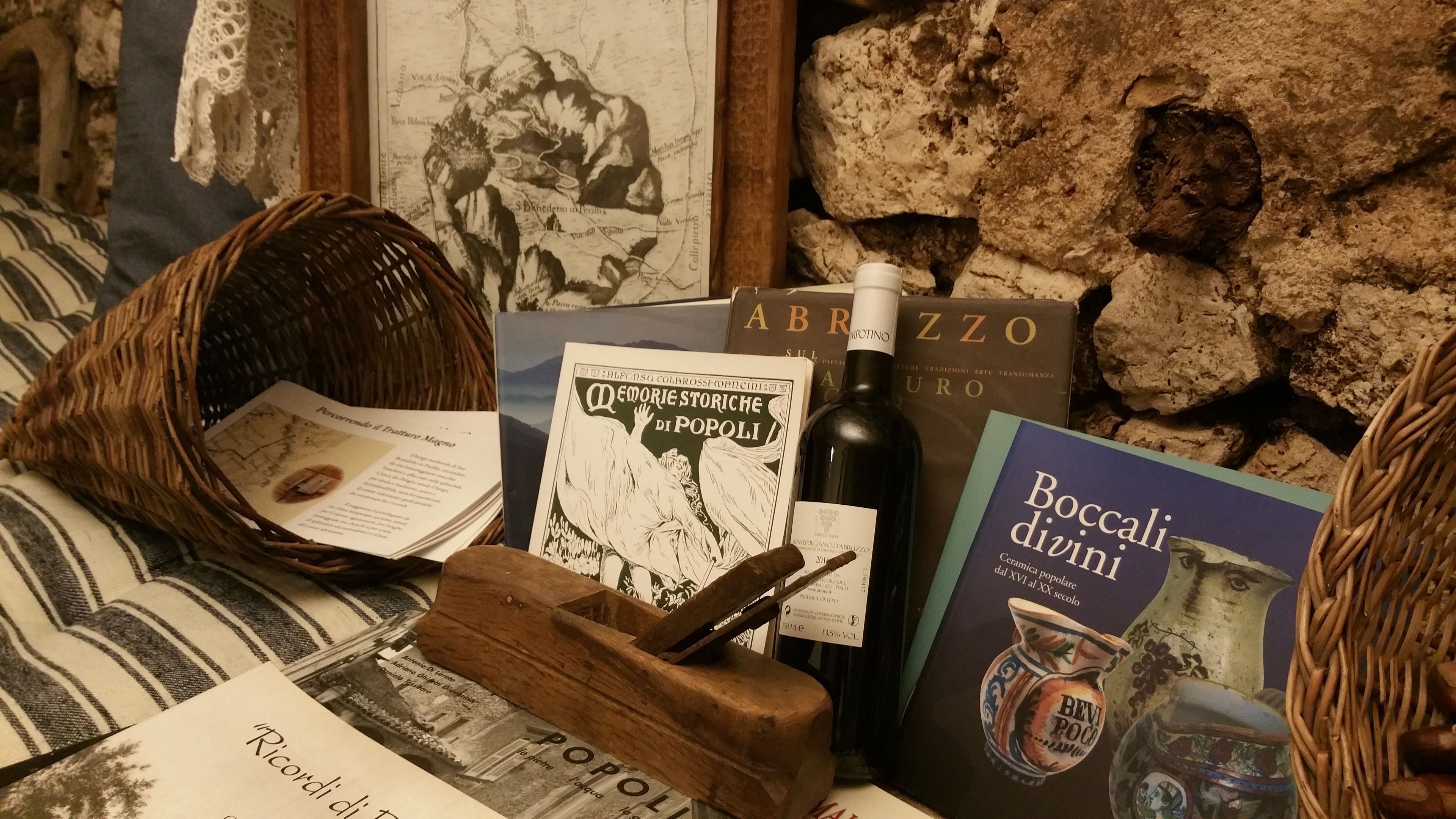 A rustic setting with a wicker basket, books, and a wine bottle on a table.