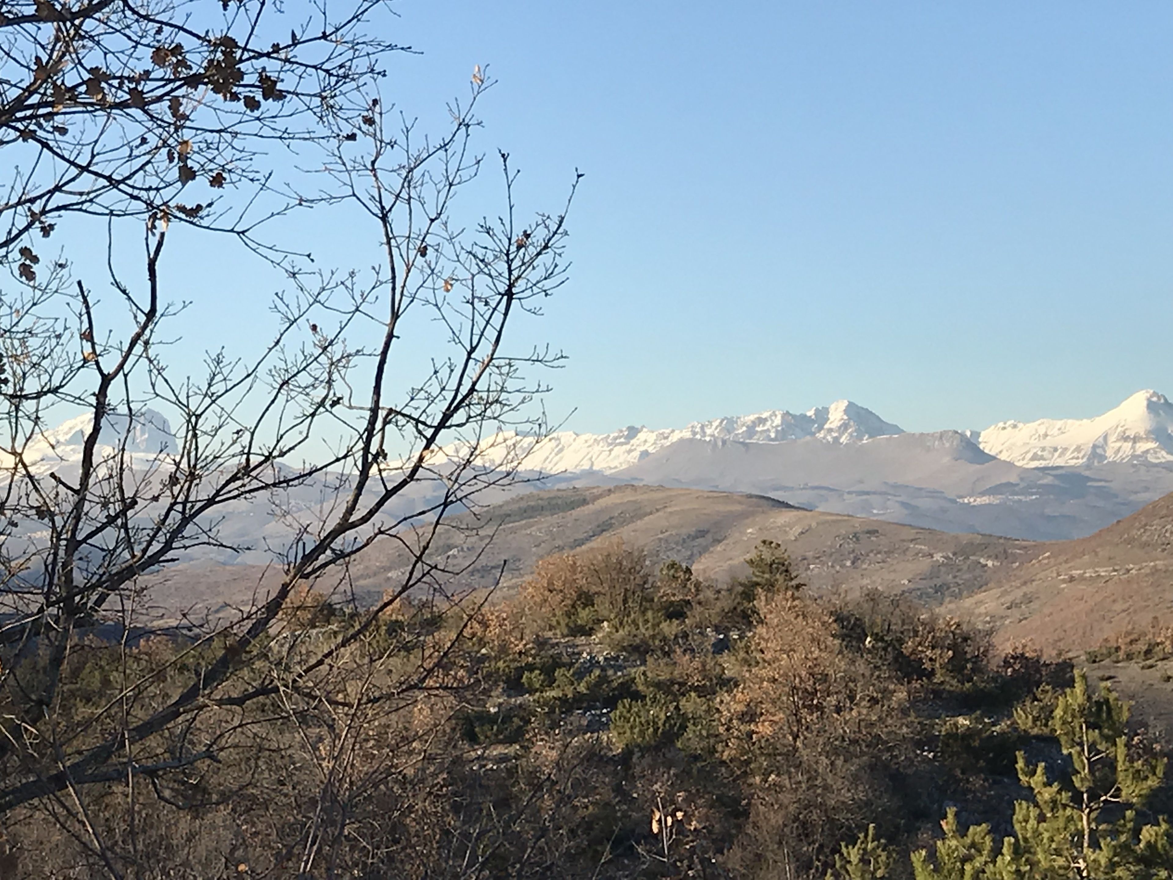 A mountainous landscape with snow-capped peaks in the background and sparse vegetation in the foreground.
