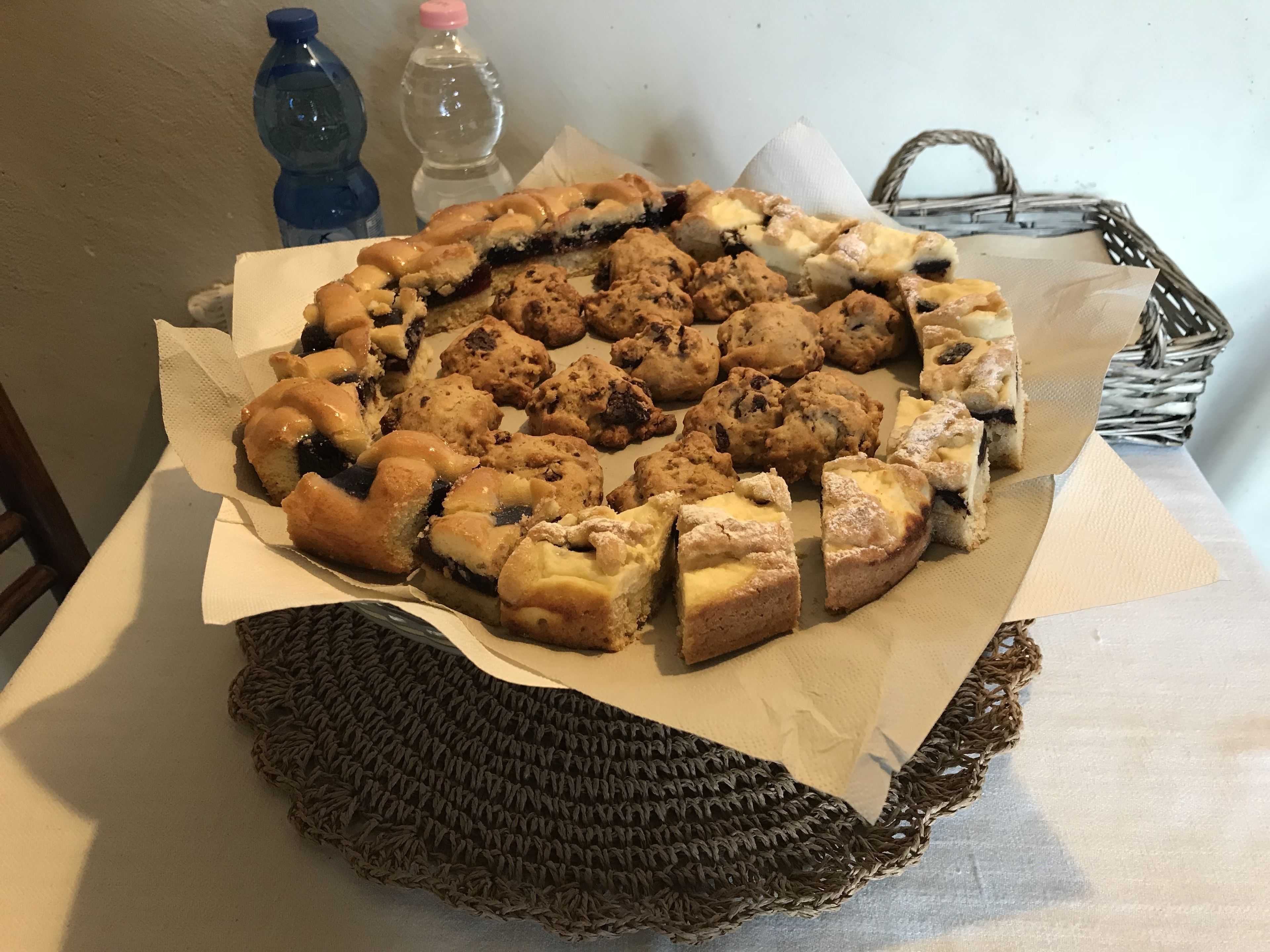 A table with a variety of baked goods, including pastries and cookies, arranged on a white paper.