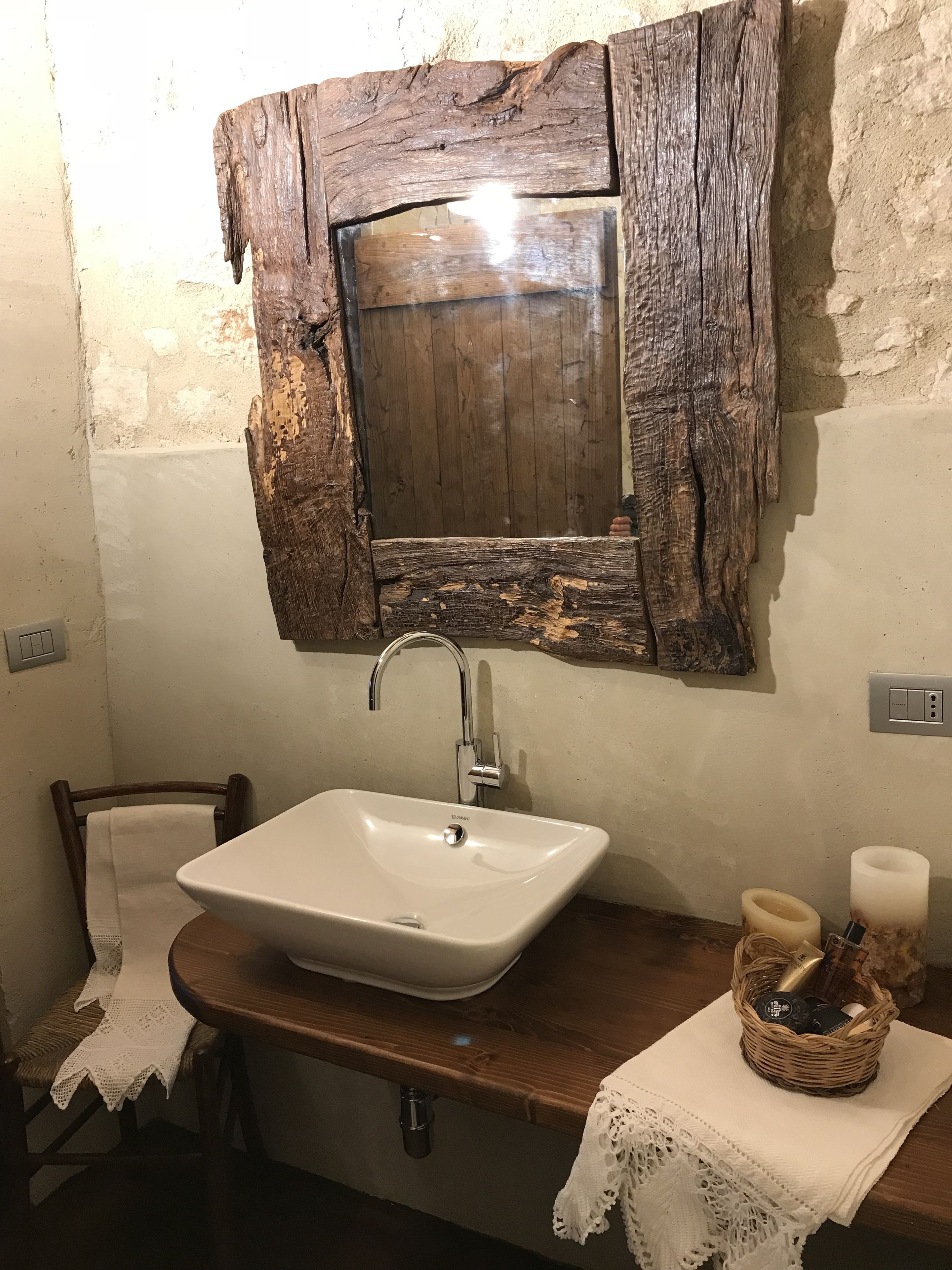 A bathroom with a rustic wooden mirror, a white sink, and a wooden vanity.