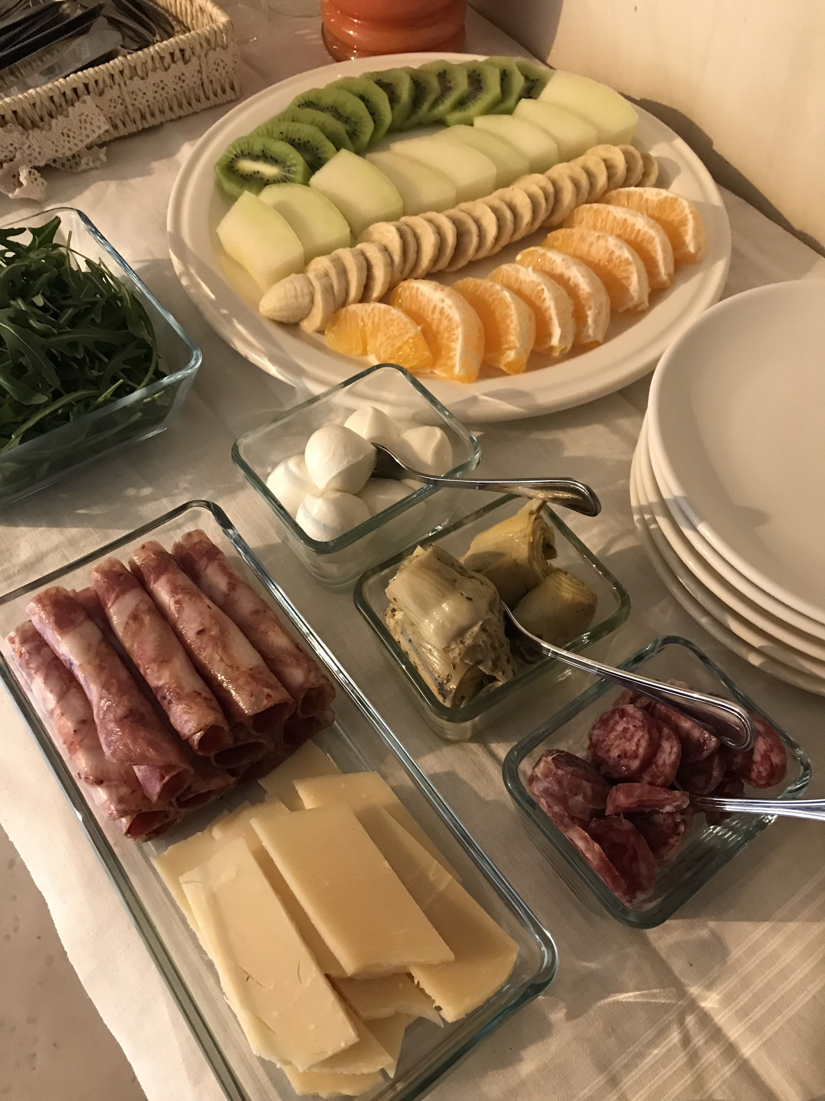 Une table garnie de divers aliments, notamment des fruits coupés en tranches, du fromage et de la charcuterie.