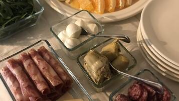Ein Tisch mit verschiedenen Speisen, darunter Obstscheiben, Käse und Fleisch.