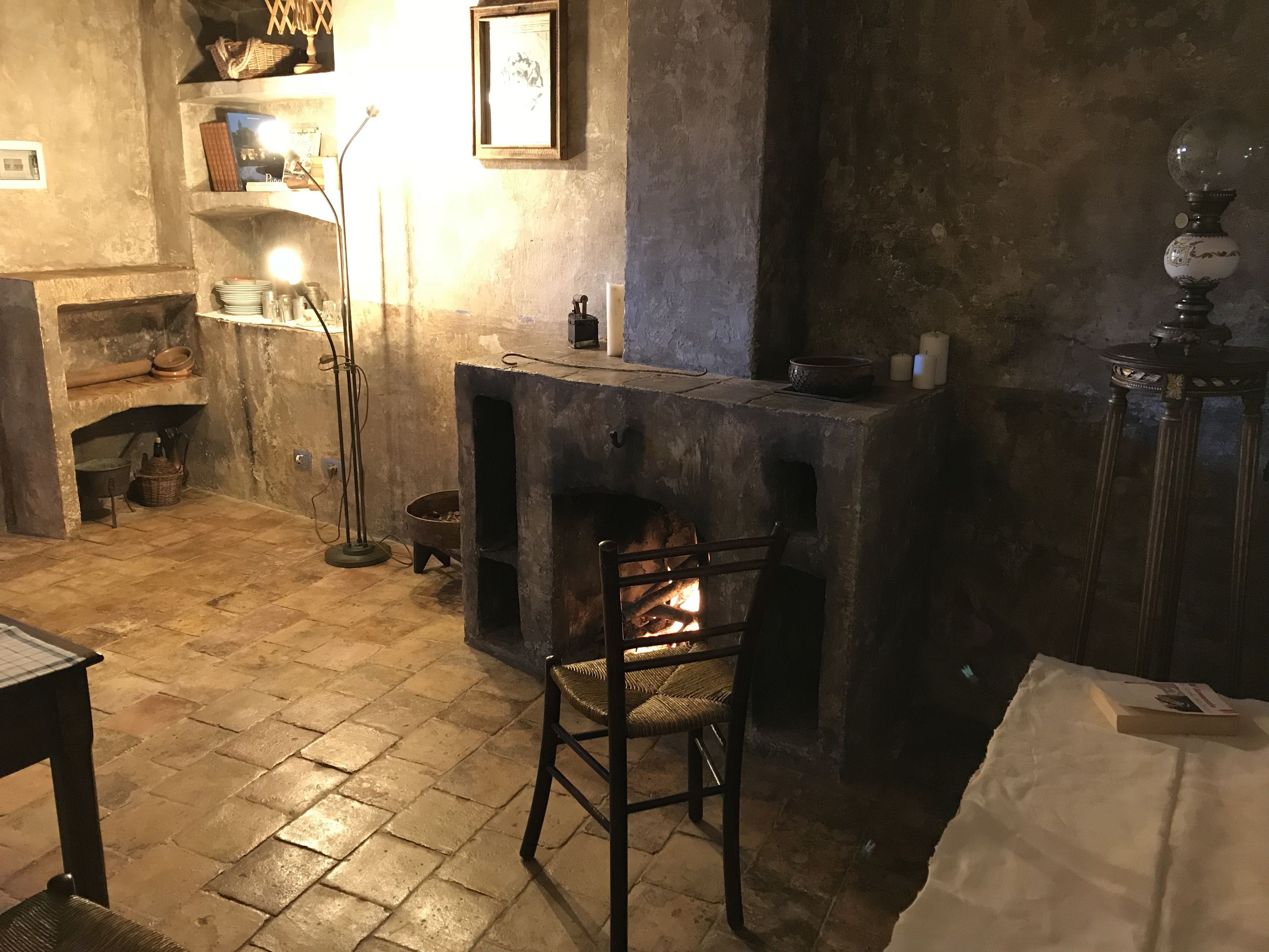 Una habitación acogedora con chimenea, una mesa con una vela y una silla.