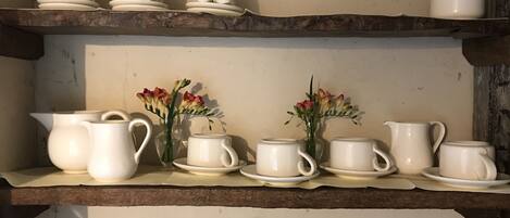 Una cocina con vajillas y jarras de cerámica blanca sobre estantes de madera.