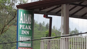 A sign for Adams Peak Inn with contact numbers.