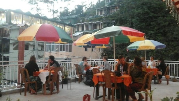 An outdoor dining area with tables and chairs, umbrellas, and a view of traditional buildings in the background.