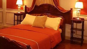 A bedroom with a wooden bed, red curtains, and two bedside lamps. - Elegant 2BRCondo in the Heart of Ortigas (Pasig)