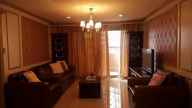 A living room with a sofa set, a coffee table, a TV, and a chandelier. - Elegant 2BRCondo in the Heart of Ortigas (Pasig)