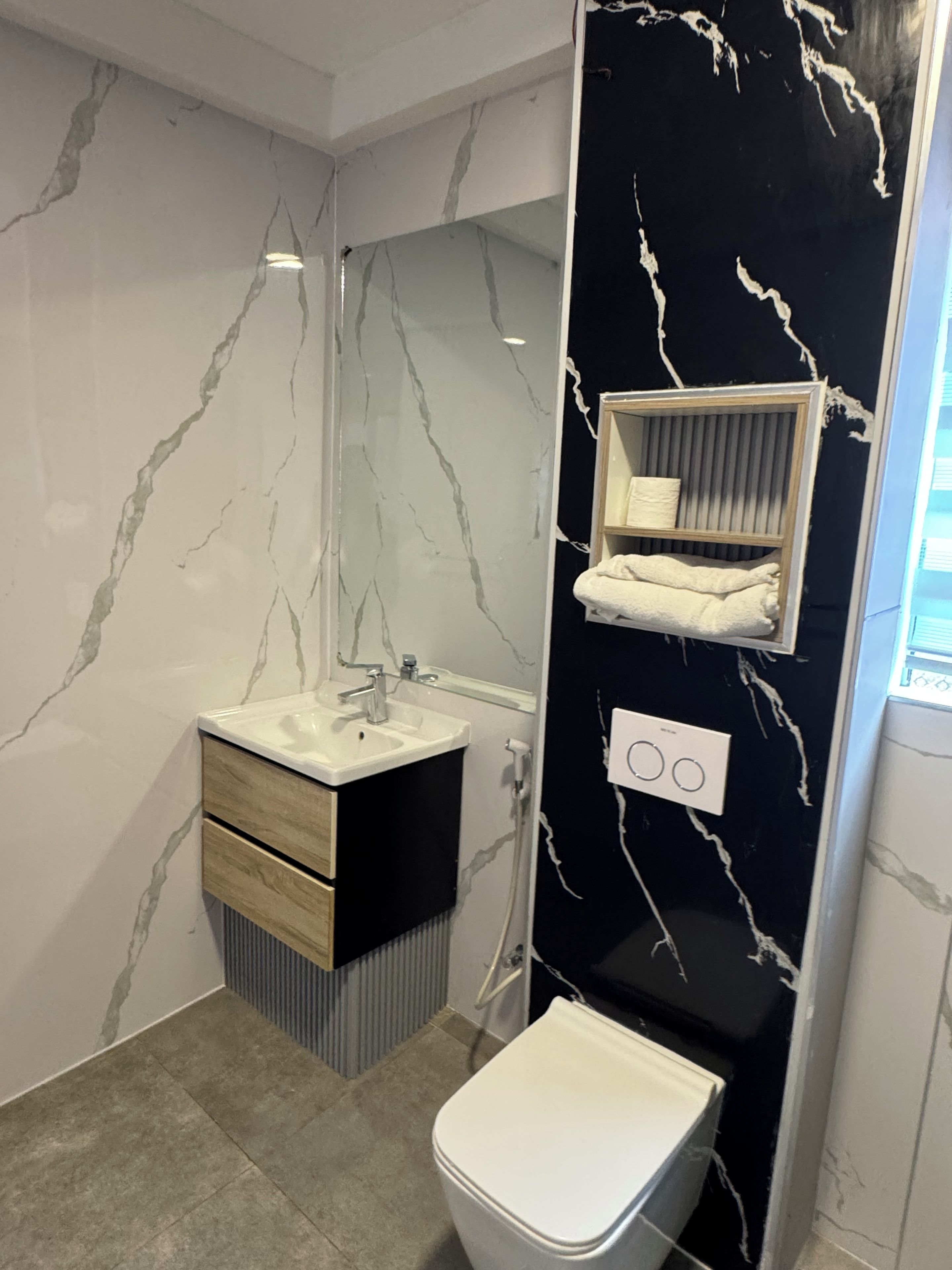 A bathroom with a white sink, a mirror, a toilet, and a towel rack.
