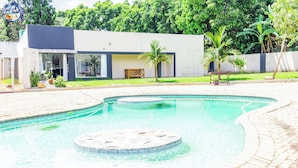 A modern building with a swimming pool, a wooden bench, and a palm tree. - Highlands Lodges and Apartments (Harare)