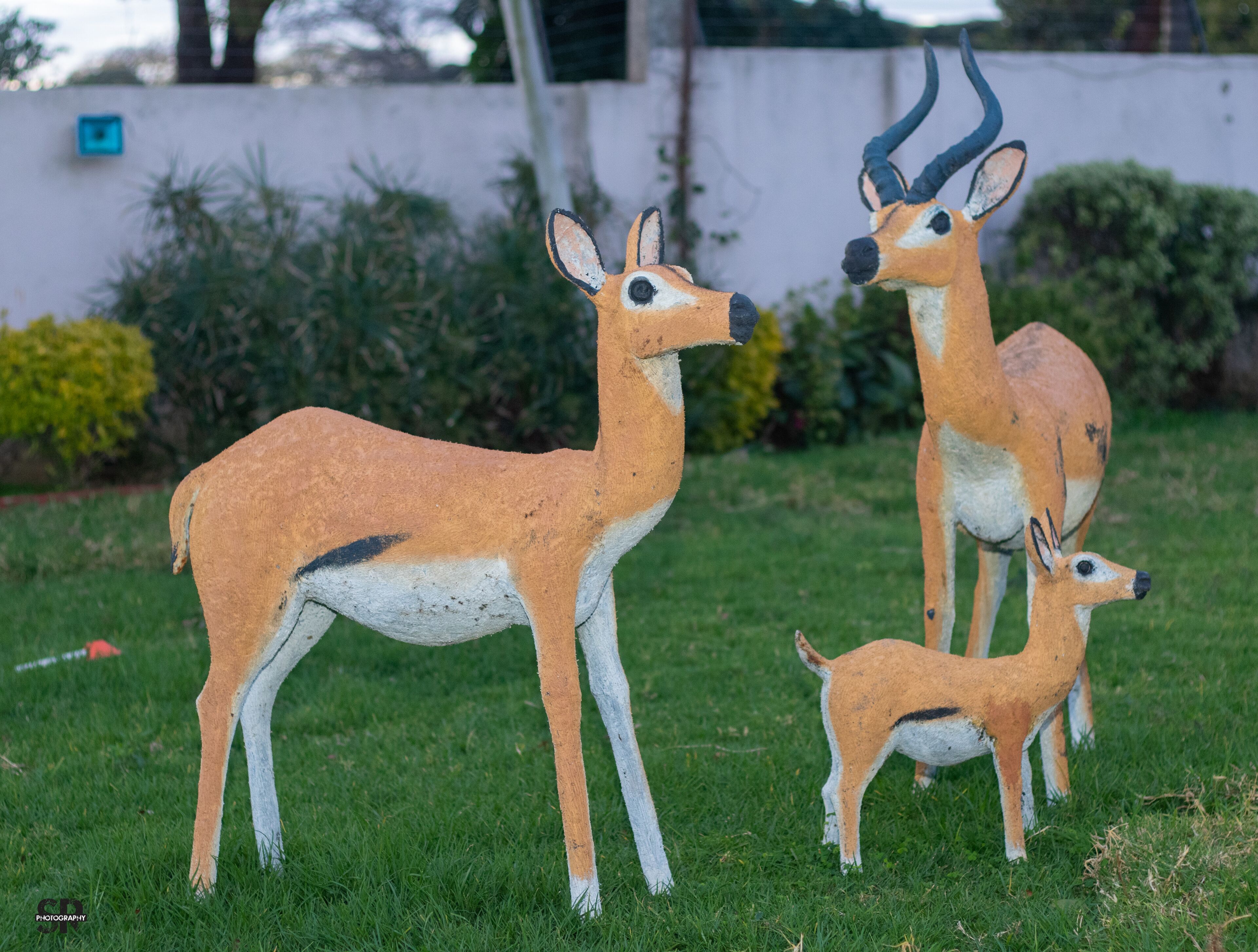 A sculpture of a deer with antlers in a grassy area.
