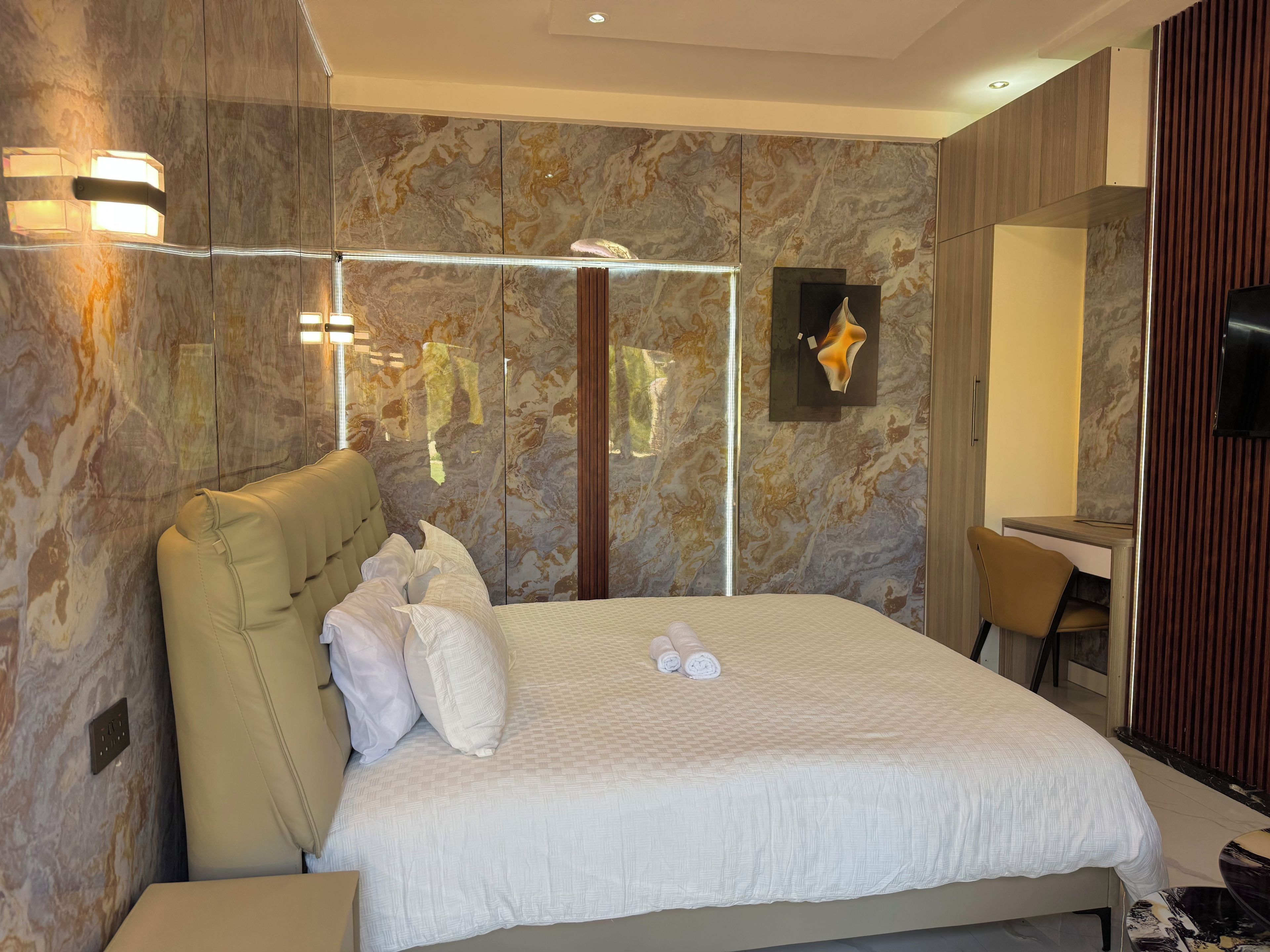 A modern hotel room with a large bed, a seating area, and a television.