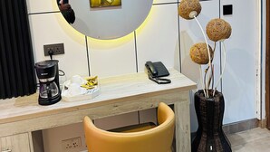 A modern office space with a desk, chair, coffee maker, phone, and decorative items. - Highlands Lodges and Apartments (Harare)