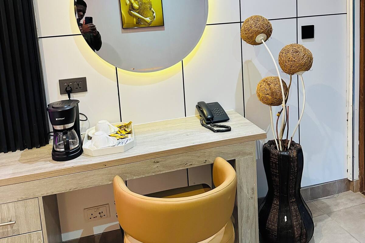 A modern office space with a desk, chair, coffee maker, phone, and decorative items.
