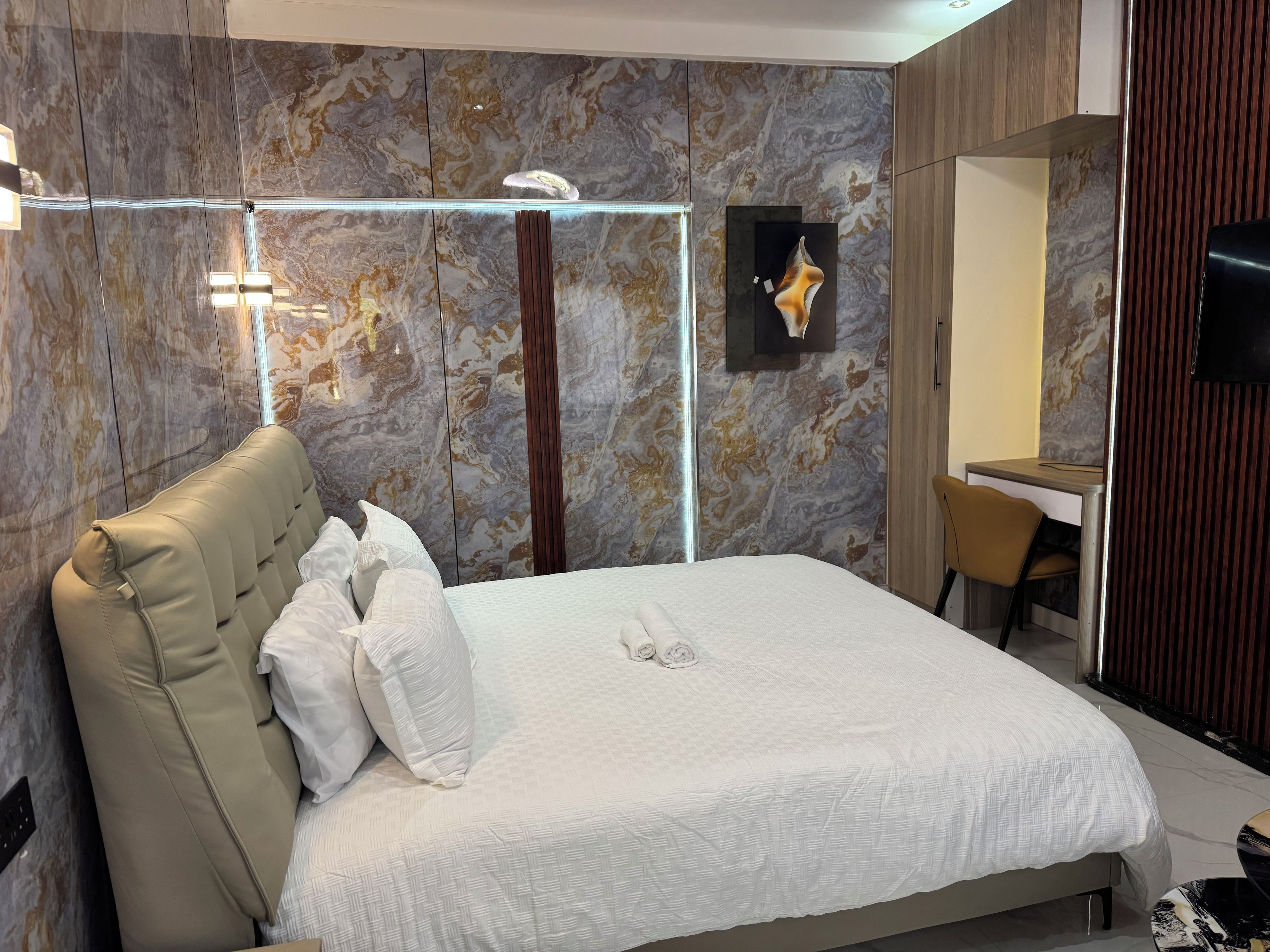Un dormitorio moderno con una cama grande, un escritorio y una televisión.