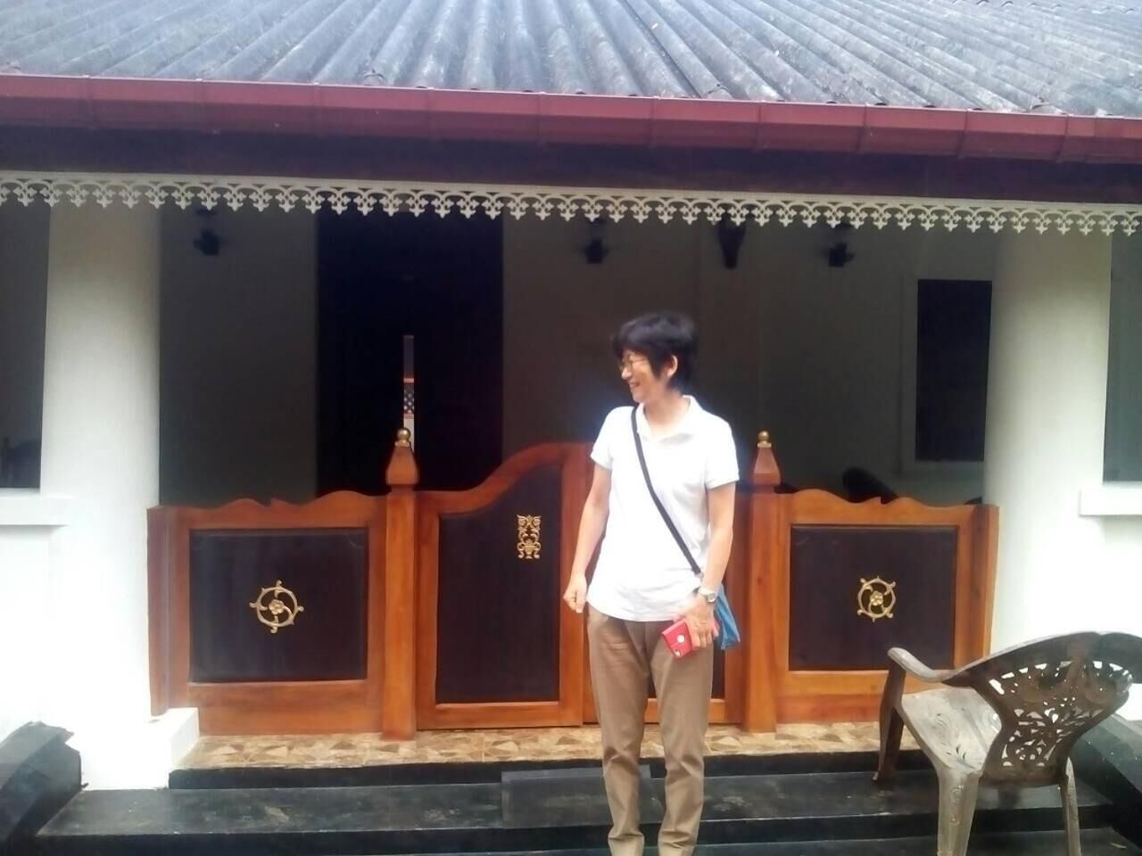 A person standing in front of a building with a decorative entrance and a wooden door with a ship's wheel emblem.