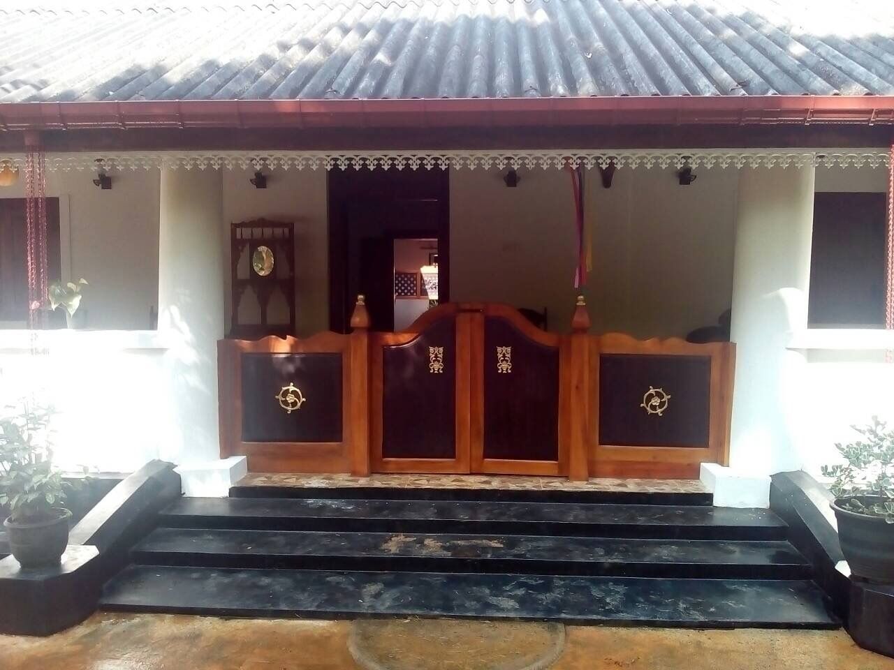 A traditional building with a tiled roof, a wooden gate with decorative elements, and a staircase leading to the entrance.