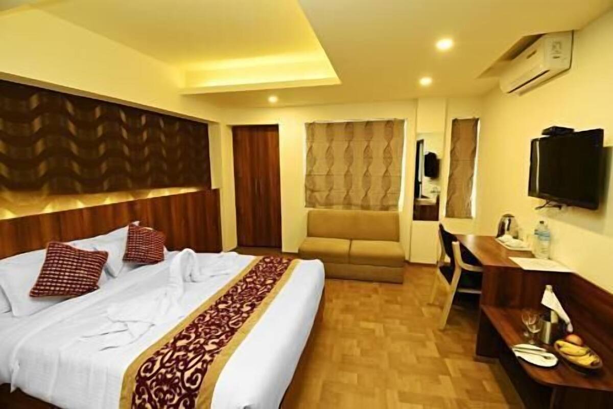 Una habitación de hotel con cama, sofá, escritorio y televisor.