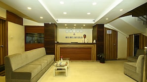 A hotel reception area with a reception desk, a sofa, a coffee table, and a staircase. - Hotel Royal Suite (Kathmandu)