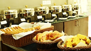 A buffet setup with baskets of bread and a row of covered food dispensers. - Hotel Royal Suite (Kathmandu)