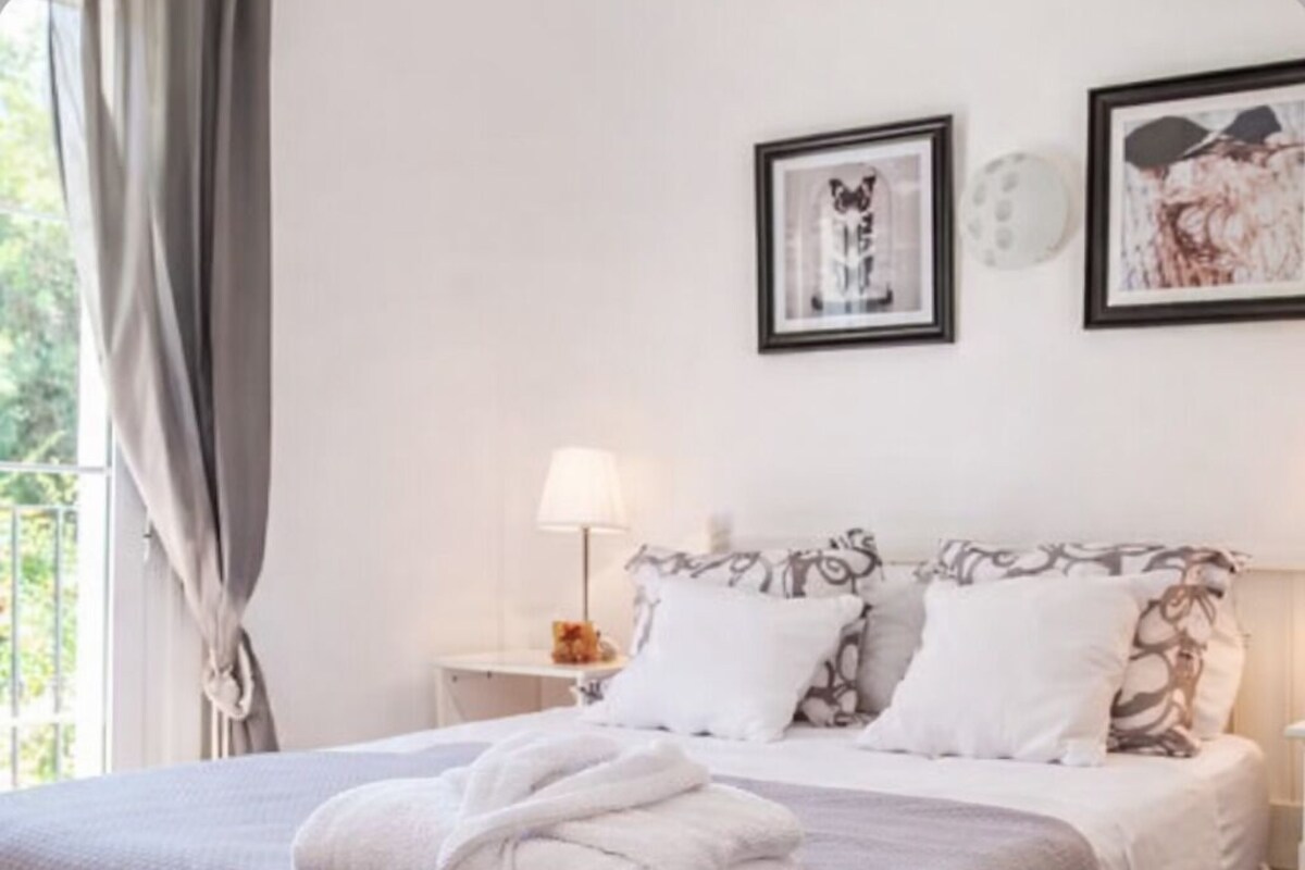 A neatly made bed with a folded towel, a bedside lamp, and two framed pictures on the wall.