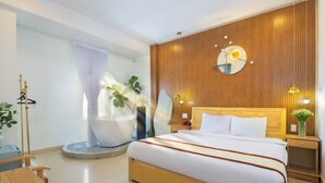 Un dormitorio moderno con una cama grande, paneles de madera, un espejo redondo, lámparas de noche, una bañera y una pequeña mesa con sillas.