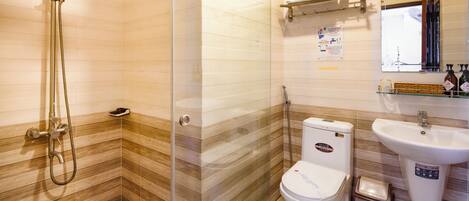 A bathroom with a shower, toilet, sink, and a mirror.