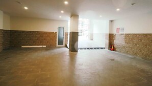Un vestíbulo amplio con una pared de acento de piedra, una puerta y un extintor.