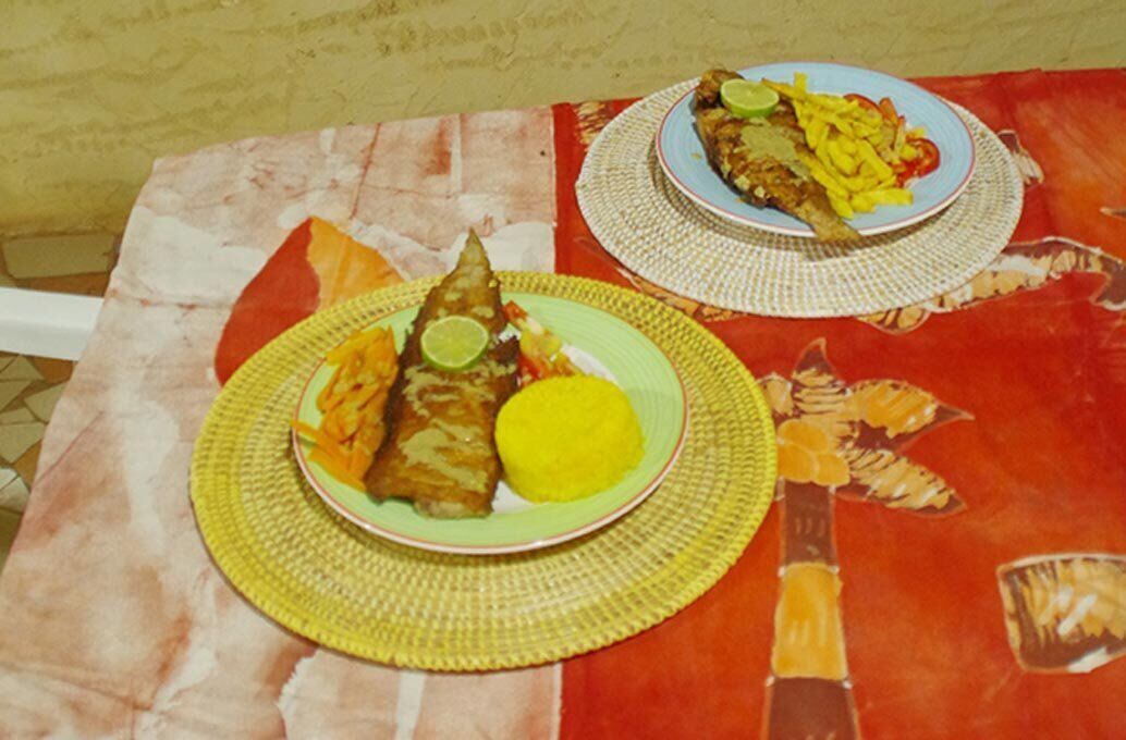 Taula amb un solleder de fibra i un plat de menjar, incloent un peix i una guarnició groga.