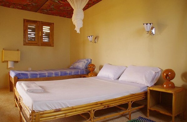 Una habitación con dos camas, una mosquitera y una mesita con lámpara.