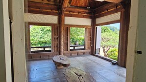 Una habitación tradicional de madera con suelo de tatami, ventanas amplias y vistas a zonas verdes.