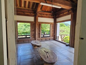 A traditional wooden room with tatami flooring, large windows, and a view of greenery. - Tohyang Gotaek (Bonghwa)