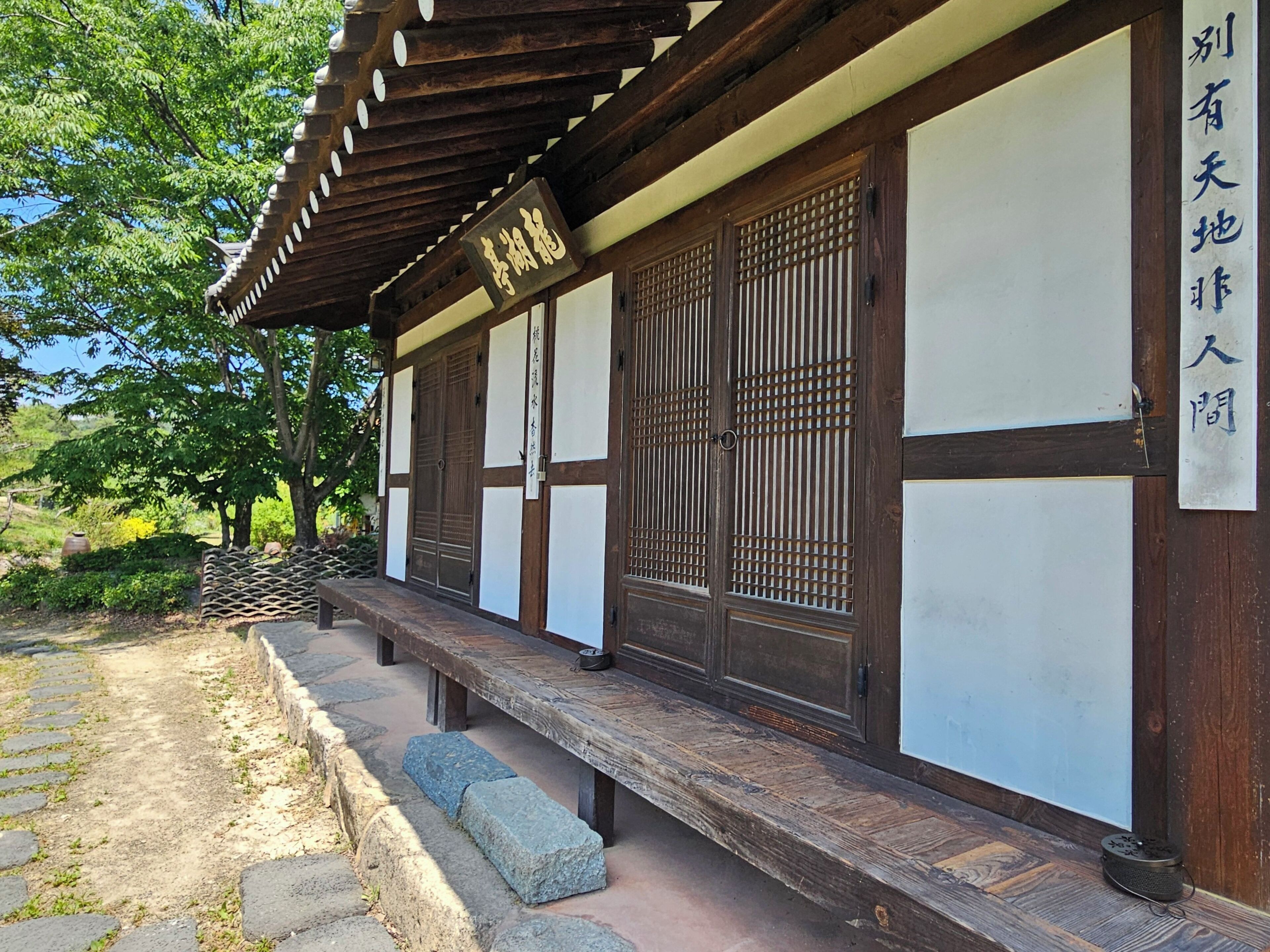 Edificio japonés tradicional con estructura de madera, pasillo cubierto y camino de piedra.