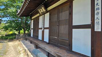 Edificio japonés tradicional con estructura de madera, pasillo cubierto y camino de piedra.