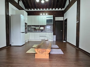 Une cuisine moderne avec des meubles blancs, une table à manger en bois et un plafond foncé.